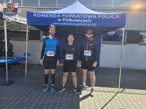 Trzech mężczyzn, którzy  stoją na tle namiotu z napisem Komenda Powiatowa Policji w Polkowicach