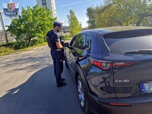 Policjant stoi przy samochodzie osobowym