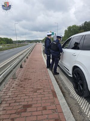 Dwóch policjantów stoi przy białym samochodzie