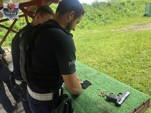 dwóch policjantów stoi przy stoliku i ładują amunicję do magazynka