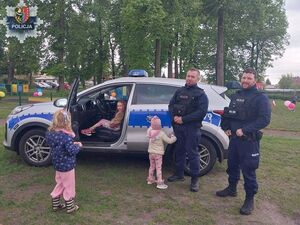 Policjanci stoją z dziećmi przed radiowozem