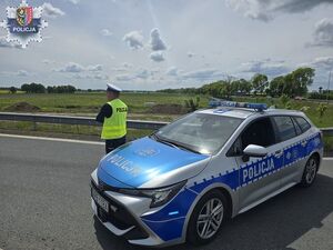 Policjant stoi obok radiowozu