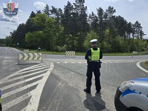 Policjant stoi obok radiowozu