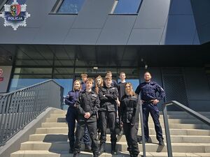 na schodach stoją policjanci i grupa uczniów z klasy mundurowej